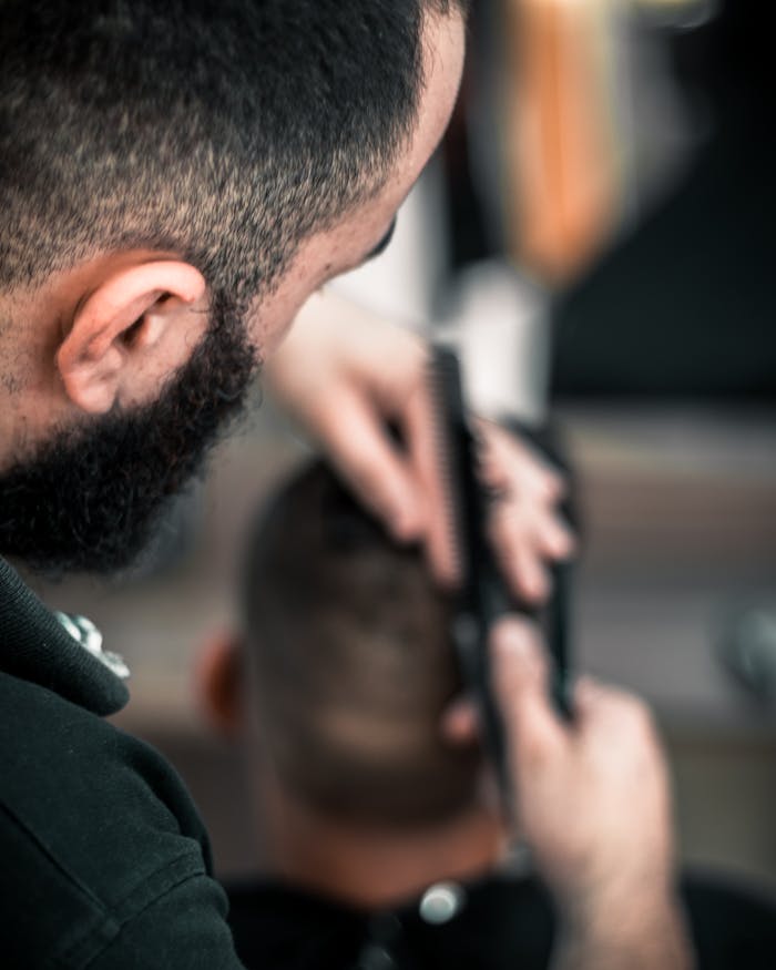 contact-img Close-up of a barber meticulously cutting a man's hair, focus on detail.